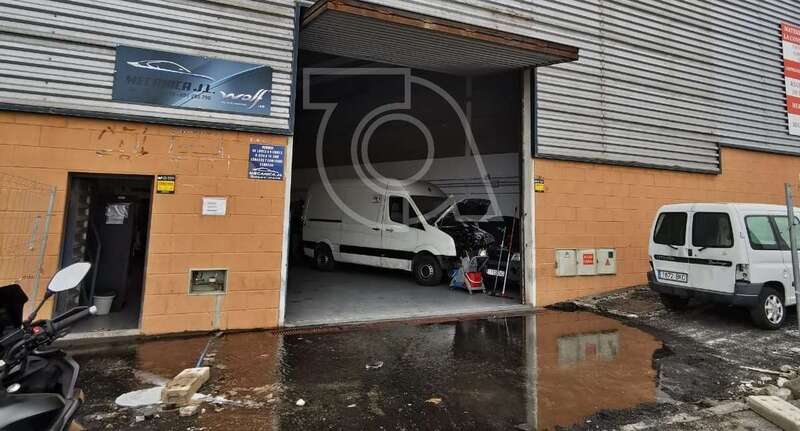 Agua encharcada delante de una de las naves industriales/TA.